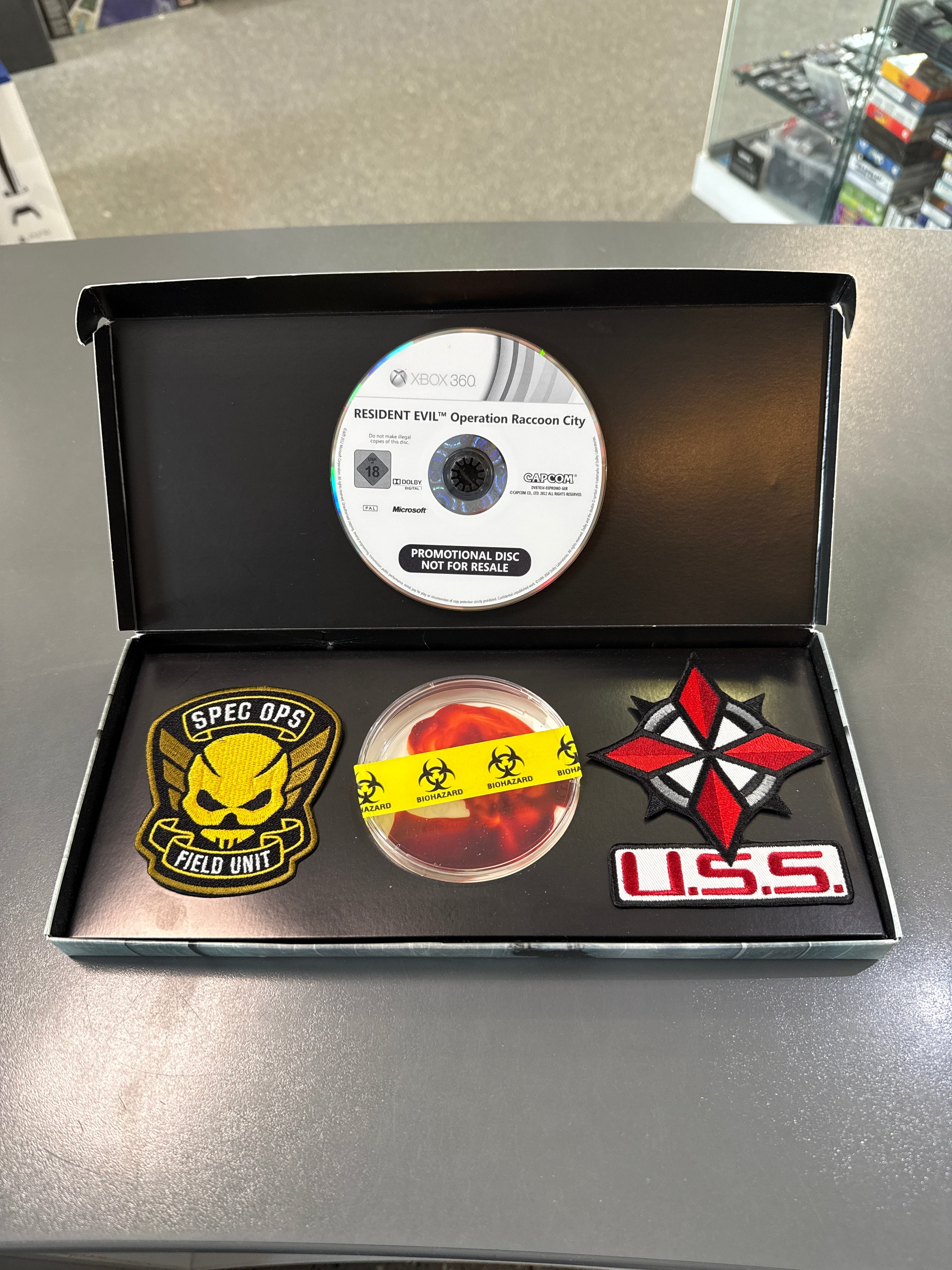 Resident Evil: Operation Raccoon City EU Press-Kit im Umbrella-Corporation-Stil mit militärischem Biohazard-Design, Soldaten der USS-Einheit, düsterer Raccoon-City-Atmosphäre und enthaltenem Promo-Material.